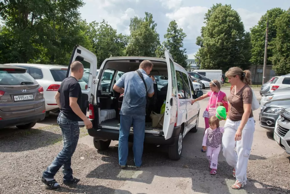 Пассажиры с багажом садятся в микроавтобус бесплатного трансфера Parking-S